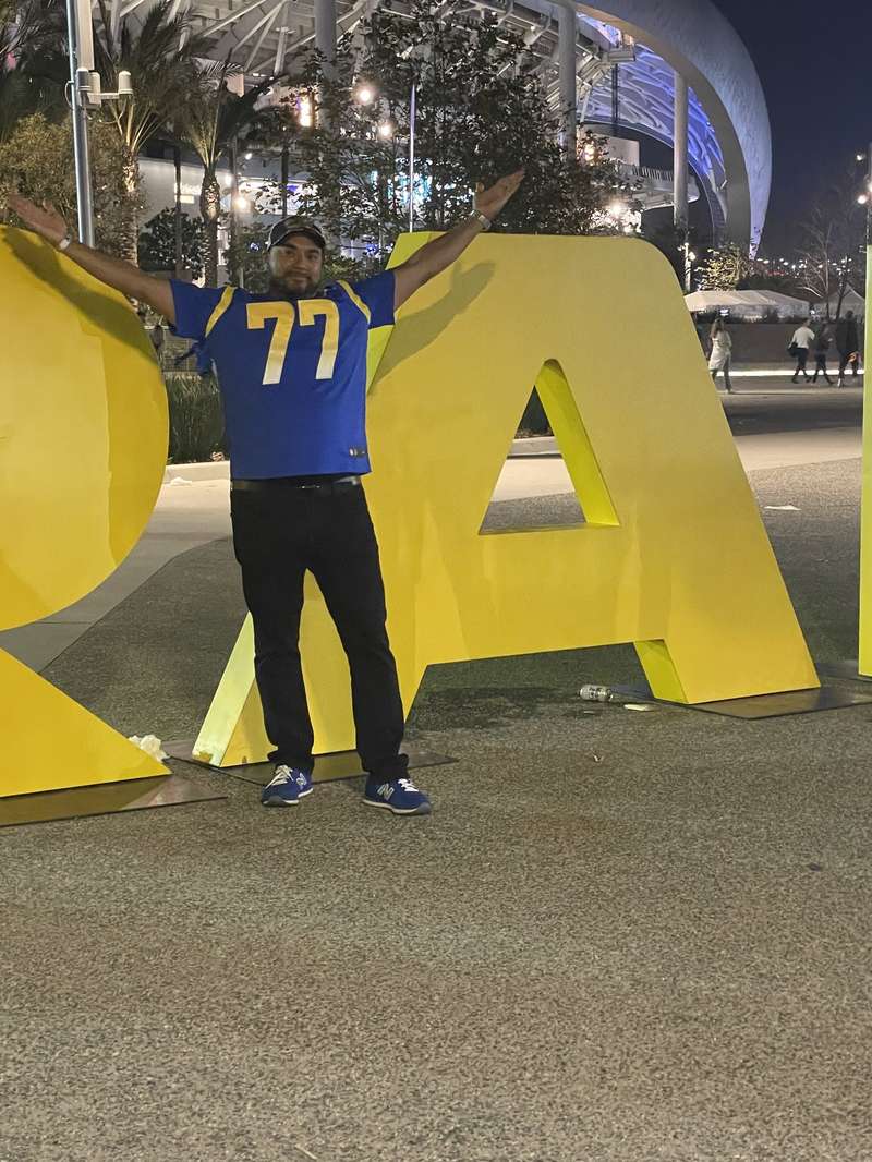 Fan posing in LA letters outside SoFi at night